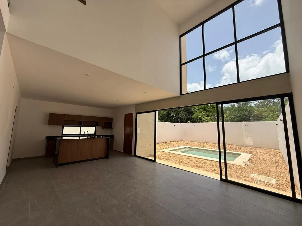Interior de doble altura del Proyecto 02, con cocina y acceso al patio con alberca
